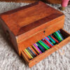 antique wooden box on wool rug filled with colour felt tips