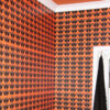 Corner of a room with a white cornice and black and orange wallpaper