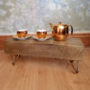 small table made from train sleeper on hairpin legs two gold cups and tea pot sitting on top